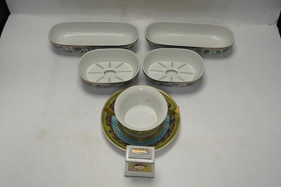 Six Rosenthal for Versace porcelain items; a boxed chocolate cup and saucer, four oblong serving dishes, longest 23cm, and a boxed miniature timepiece, 8.5cm high. Condition - good.